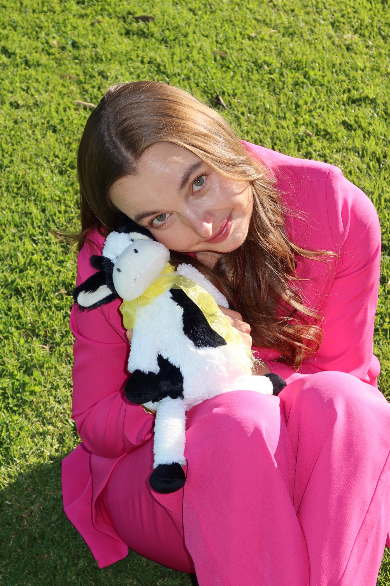 Meg Morris in a bright pink suit holding a toy cow